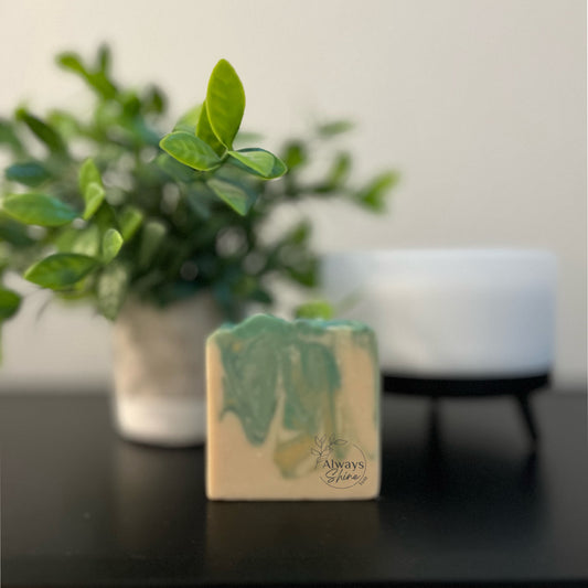 Picture displays a single bar of soap that has swirls of green, yellow and white. 